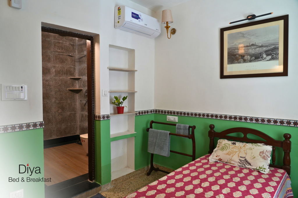 Cozy bedroom at Diya Bed & Breakfast with green-accented walls, a single bed, and an attached bathroom.