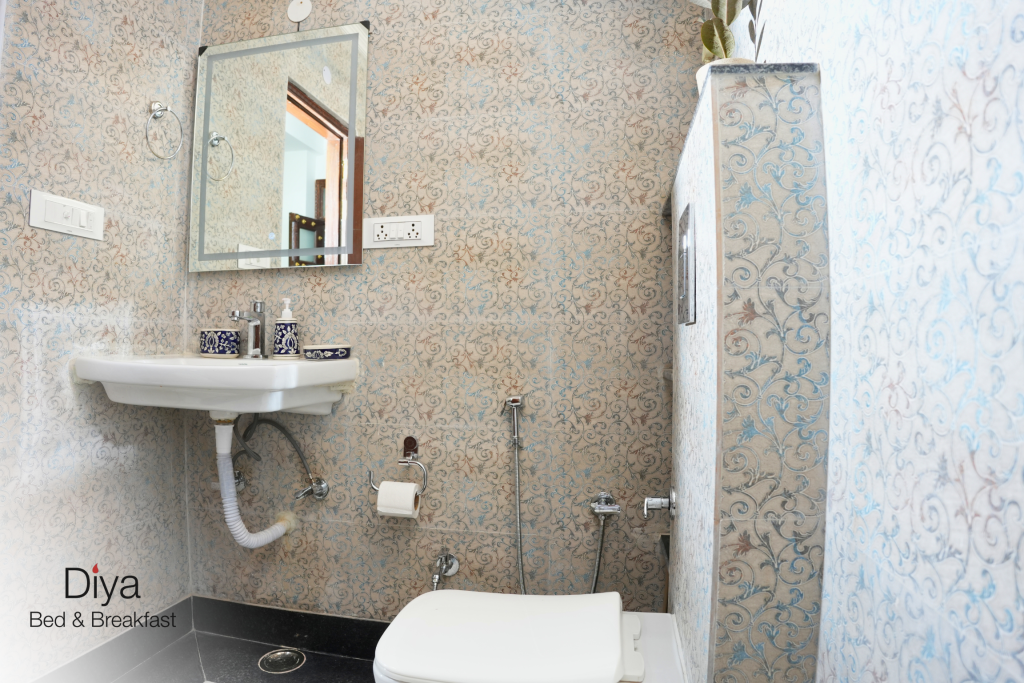 Compact bathroom at Diya Bed & Breakfast with patterned walls, a wall-mounted sink, and modern fixtures.