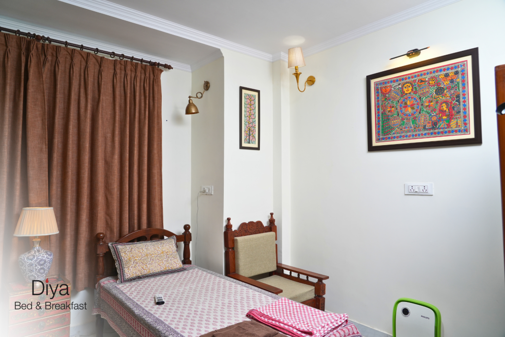 Cozy single bedroom at Diya Bed & Breakfast with traditional wooden furniture, patterned bedding, and framed artwork on the walls.