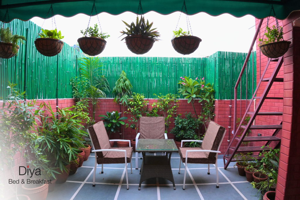 Outdoor patio with potted plants, hanging baskets, and a seating arrangement at Diya Bed & Breakfast.