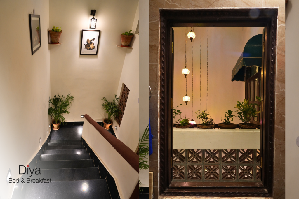 Interior of Diya Bed & Breakfast dining area with wooden tables, cushioned chairs, warm lighting, wall art, and decorative plants.