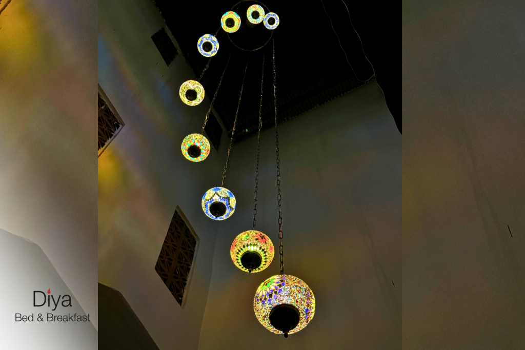 Vertical row of colorful mosaic glass hanging lamps glowing warmly at Diya Bed & Breakfast.