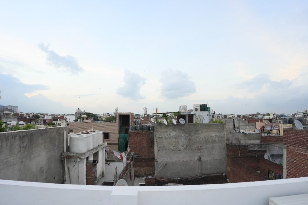 Panoramic view of urban rooftops with water tanks, satellite dishes, and scattered clouds in the evening sky.