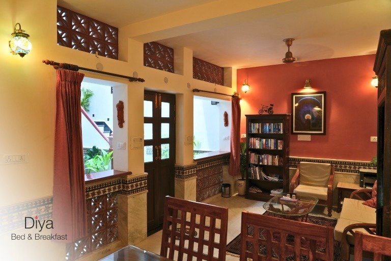 Cozy lounge at Diya Bed & Breakfast with warm lighting, bookshelves, wooden furniture, and decorative terracotta panels.